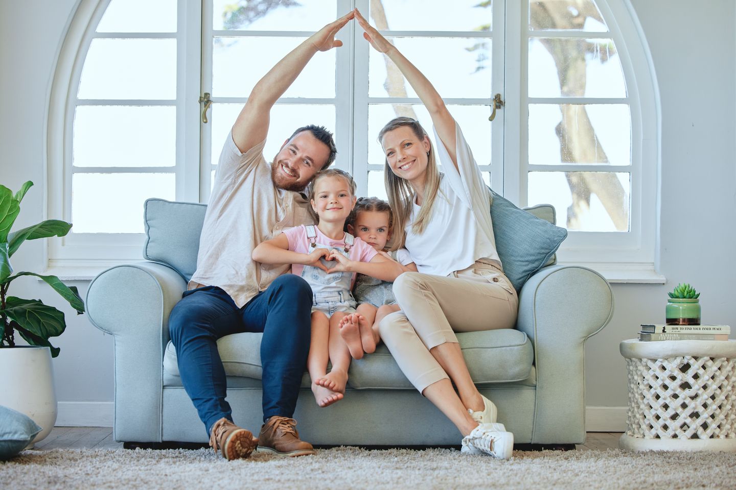 Familie auf einem Sofa formt mit den Armen ein Dach über sich